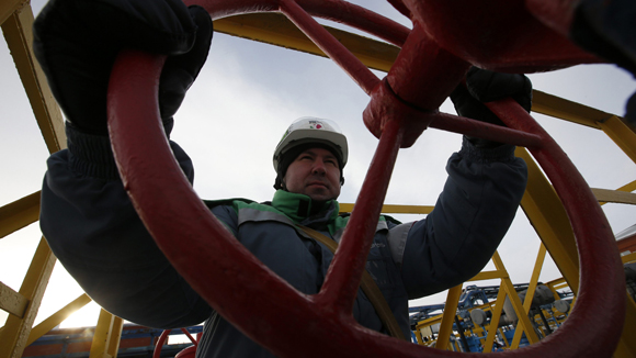 A worker adjusts the valve of an oil pipe at an oil reception and delivery point owned by Bashneft company near Kaltasy