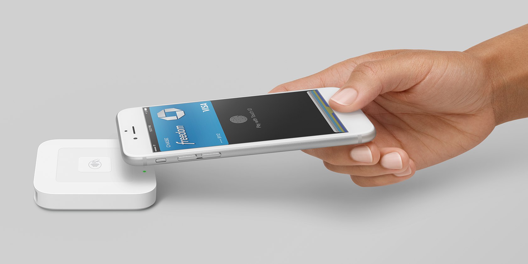 Image of hand holding iPhone paying with Apple Pay near Square contactless and chip reader