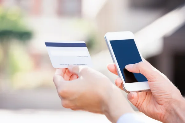 Женщина руками проведения кредитной карты и с помощью ячейки, смарт-телефон — стоковое фото