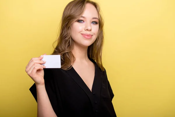 Молодая женщина, держащая банковской карты, изолированные на желтом фоне — стоковое фото